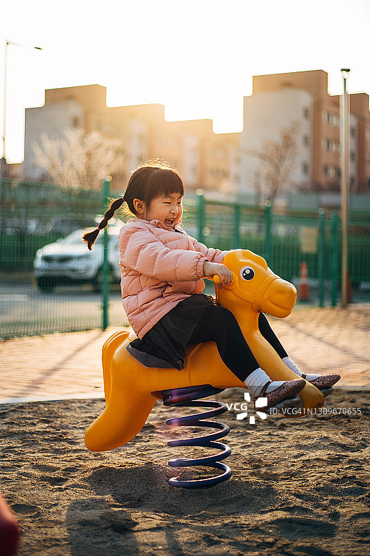 快乐小女孩在操场骑马图片素材
