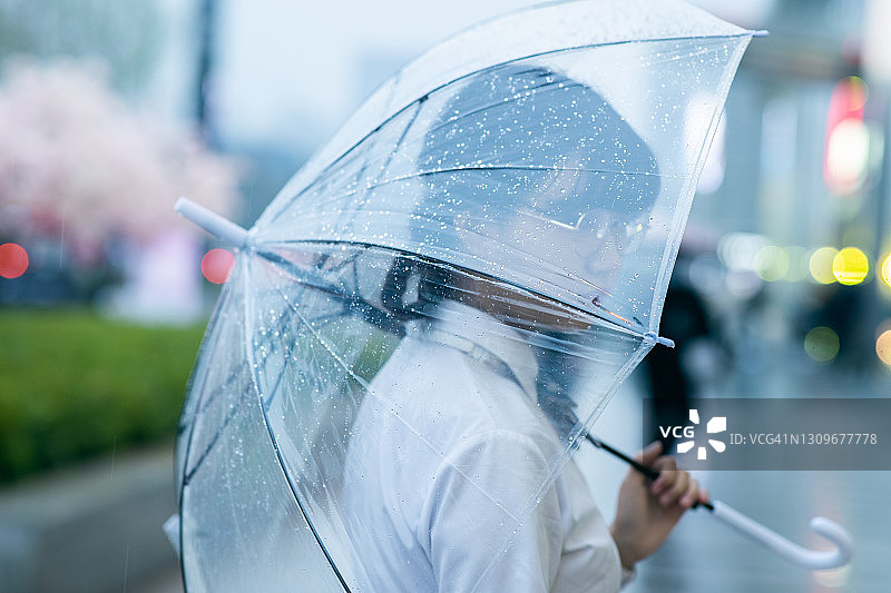 悲伤的青少年女孩在雨中撑伞图片素材
