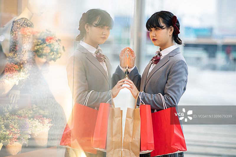 看着商店橱窗的年轻女孩图片素材