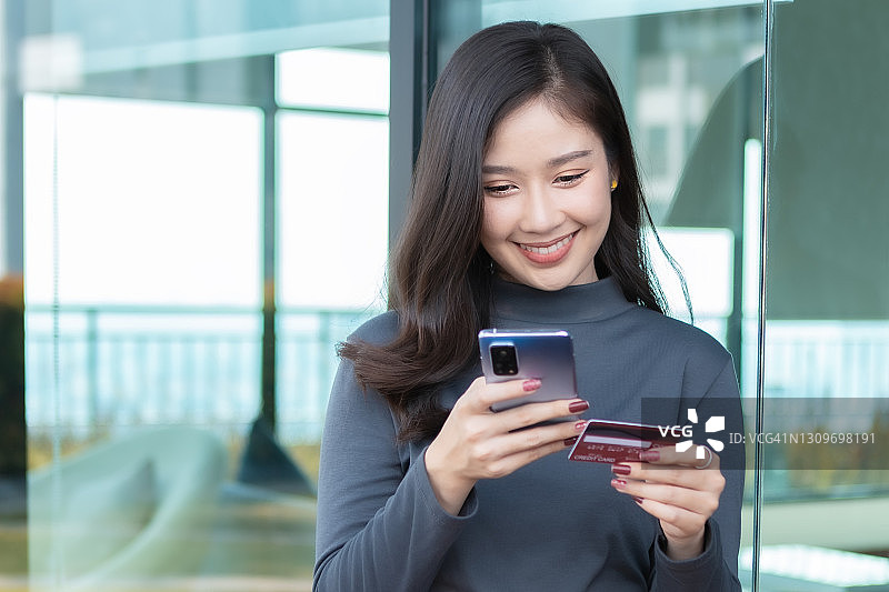 亚洲女人手持智能手机购物图片素材