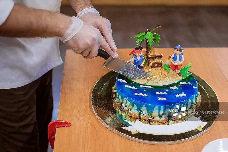 戴手套的手用刀切生日蛋糕特写图片素材