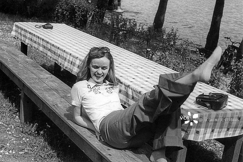 年轻女人在长椅上伸腿，玩得很开心图片素材