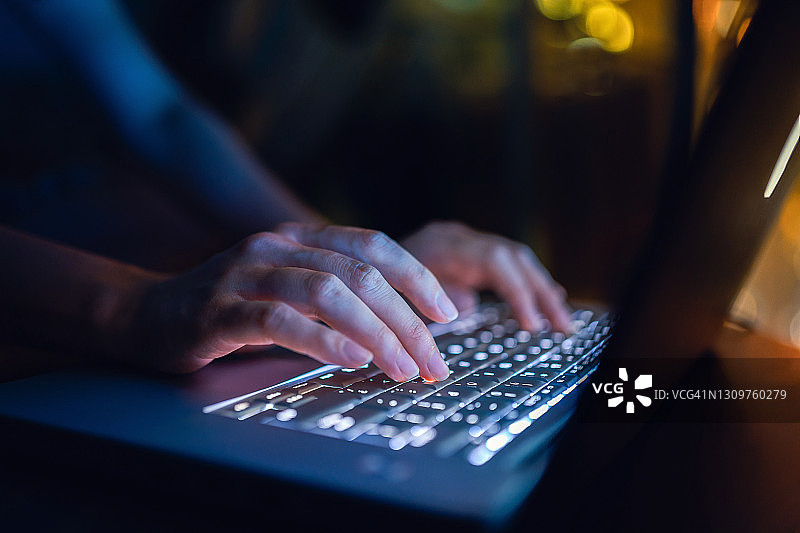 女子深夜在家用笔记本电脑打字特写图片素材