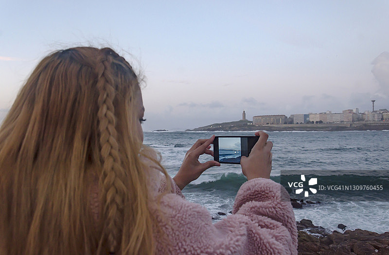 年轻女人在日落时拍摄美丽的拉科鲁尼亚城市图片素材