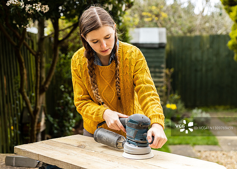 年轻个体户使用回收材料制作家具，进行环保木工工作图片素材
