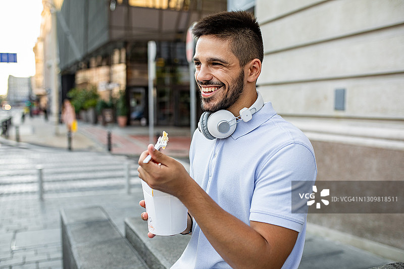 年轻男人休息时吃快餐。图片素材