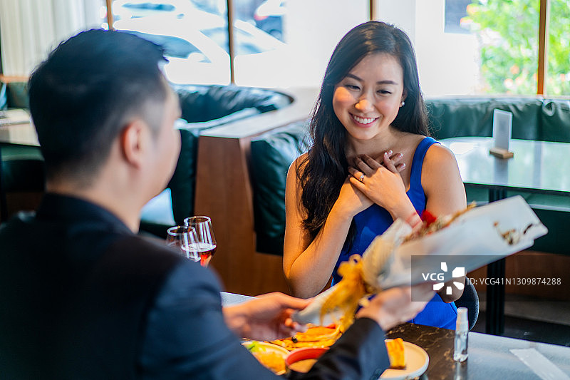 在餐厅里，惊讶的亚洲女人收到男友的鲜花图片素材