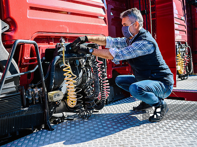 戴口罩的卡车司机检查卡车的正确性图片素材