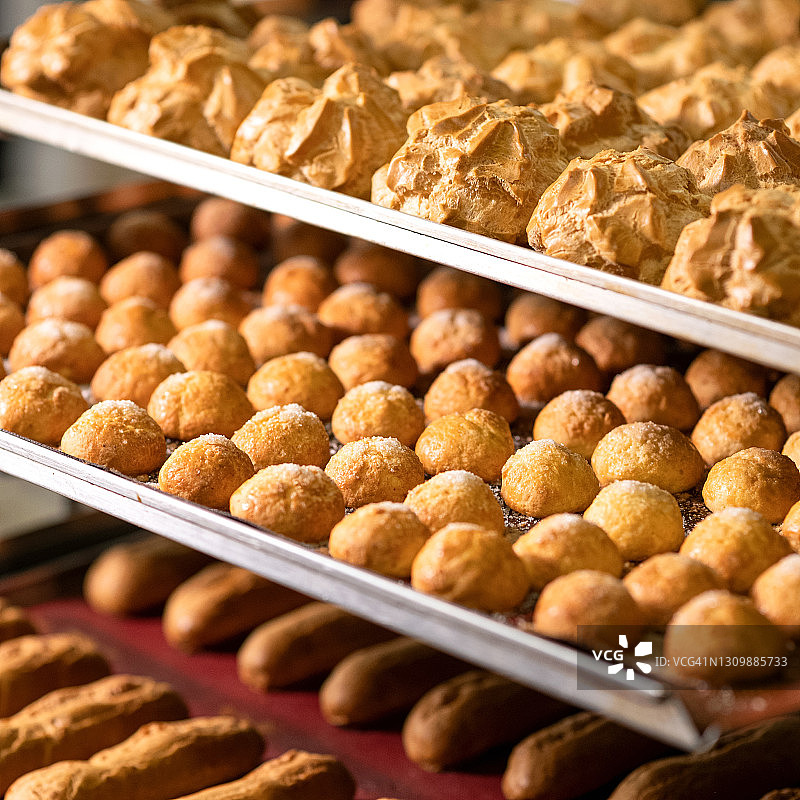 货架上的泡芙和长条蛋糕，泡芙糕点，新鲜烘焙面团，甜点背景，方形构图，柔焦图片素材