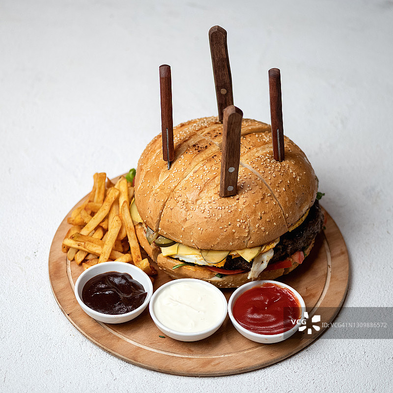 切成四份的巨型汉堡，配有炸薯条和各种酱料，适合多人分享的美食快餐，俯视图图片素材