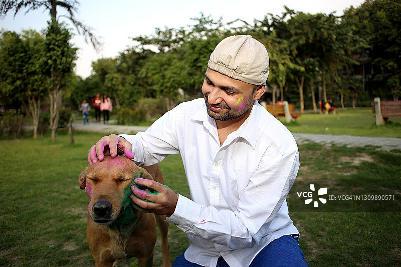 宠物主人和狗一起玩洒红节图片素材