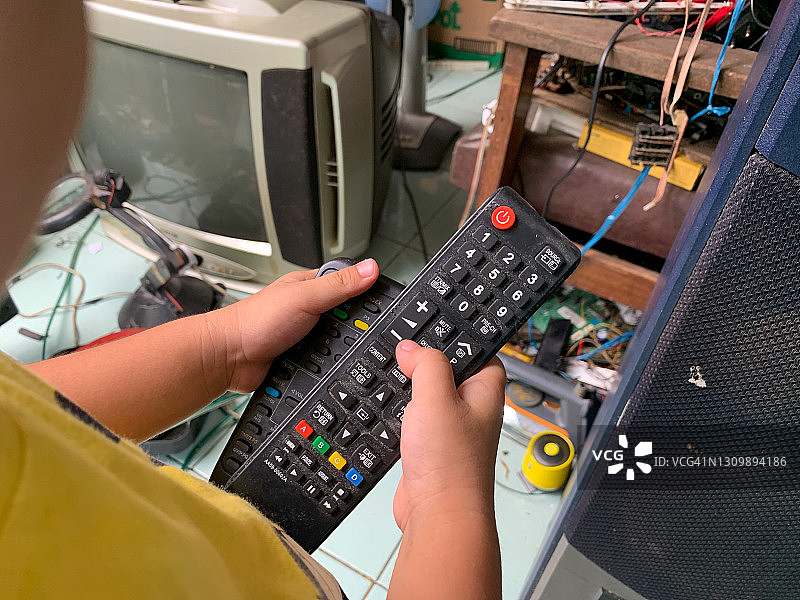 手持电视遥控器的亚洲男孩图片素材