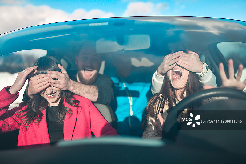 在雪地里乘车时，男人恶作剧地蒙住女人的眼睛图片素材