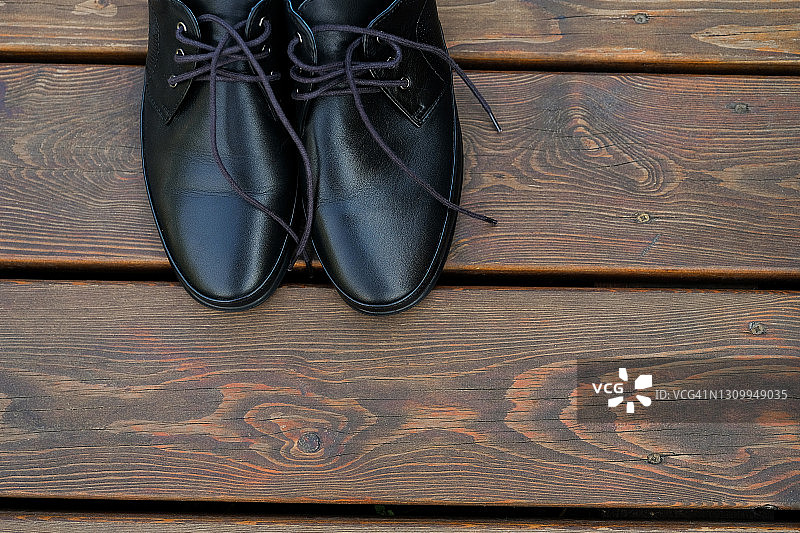 木地板上的黑色优雅商务男士皮鞋特写。由闪亮漆皮制成的新款奢华现代时尚新郎鞋、商人鞋或企业家鞋。有文案空间。图片素材