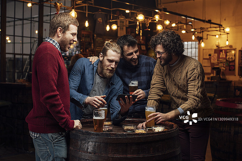 在酒吧的快乐聚会：一群快乐的年轻男人在喝啤酒时自拍图片素材
