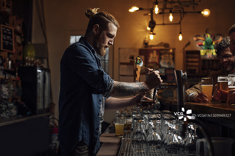 金发酒保在酒吧倒啤酒侧视图图片素材