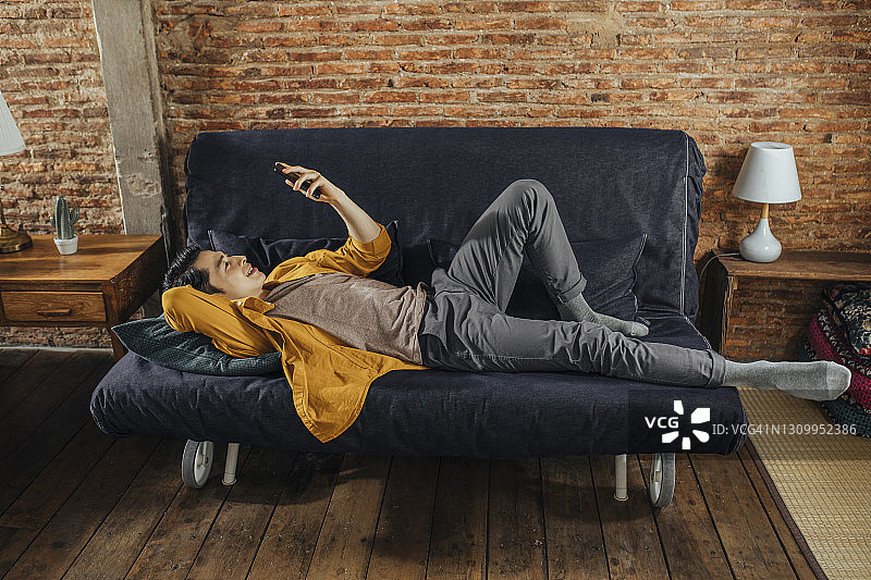 年轻学生在沙发上放松并与朋友进行视频聊天图片素材