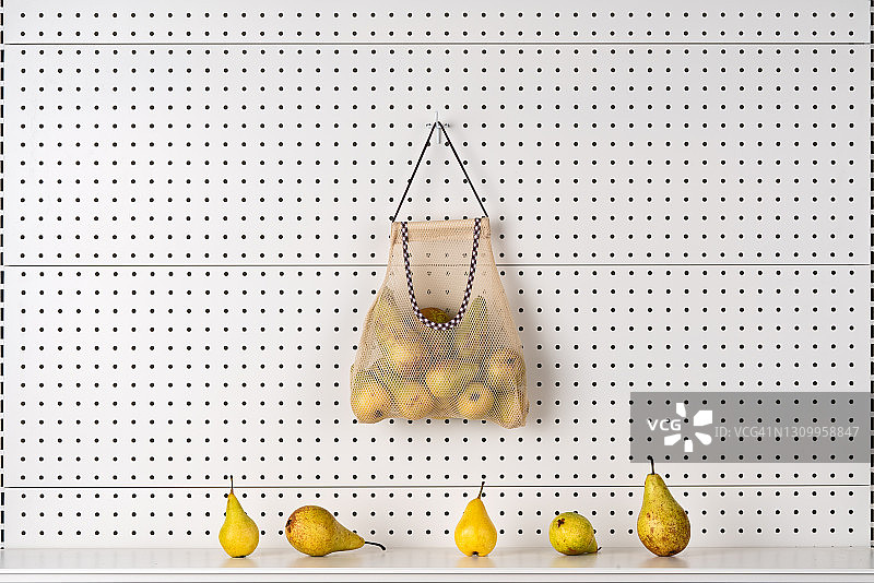 挂在钉板上的可重复使用网袋里的梨图片素材