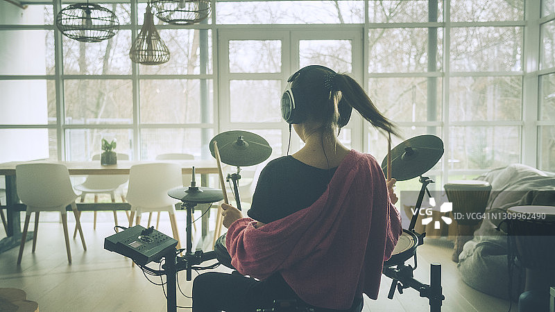 年轻女人在客厅练习电子鼓图片素材