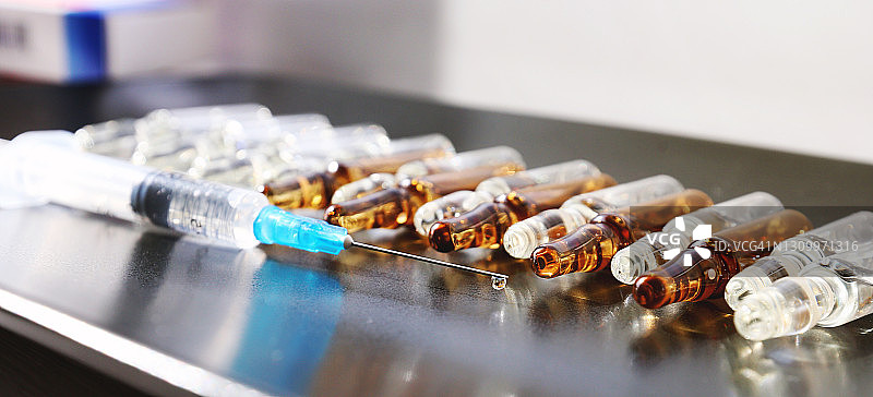 带有水滴的注射器，对着玻璃安瓿图片素材