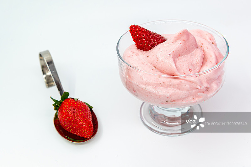 白色背景下草莓和冰沙杯旁的勺子，特写微距图片素材