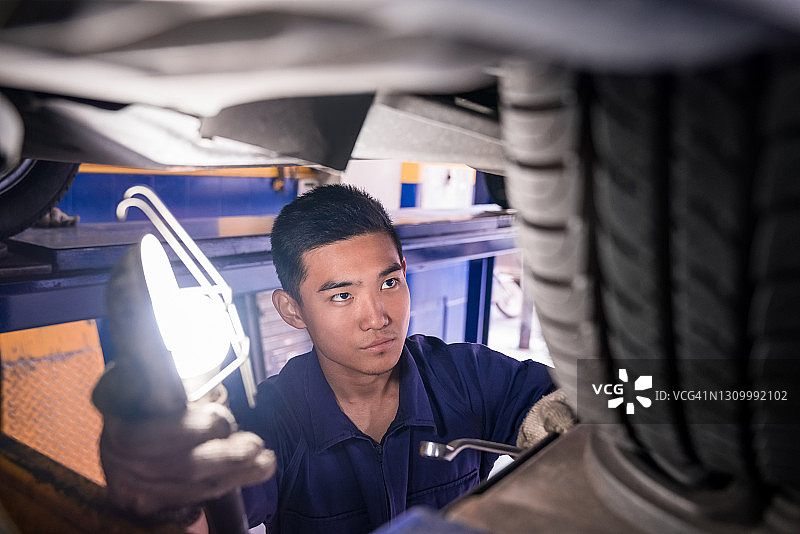 汽车修理工在车库检查车轮图片素材