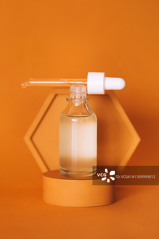 橙色背景黄色展台上的发光黄色指甲油图片素材