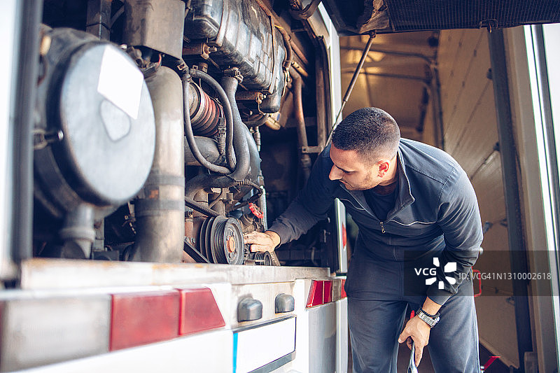 男 mechanic 正在修理公共汽车发动机图片素材