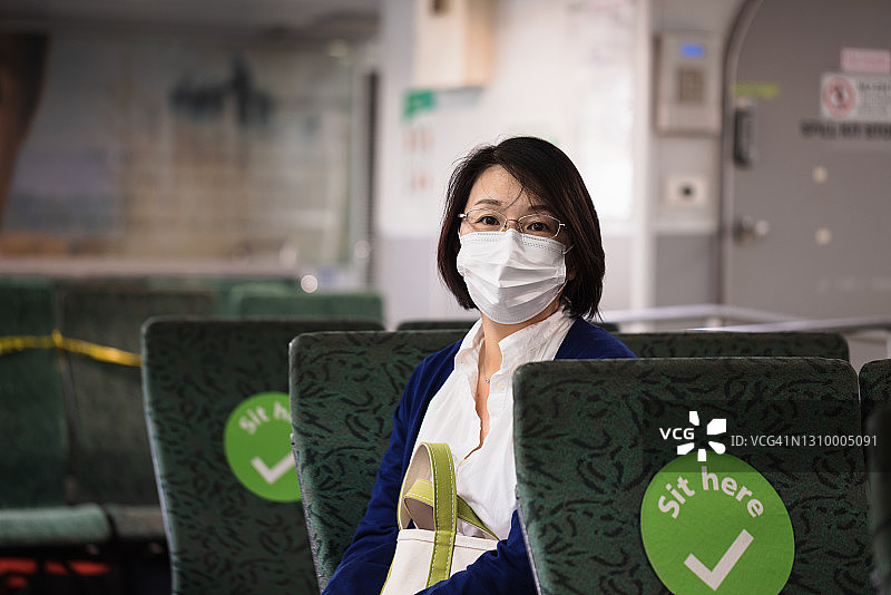 在公共交通工具上戴着口罩的亚洲女性图片素材