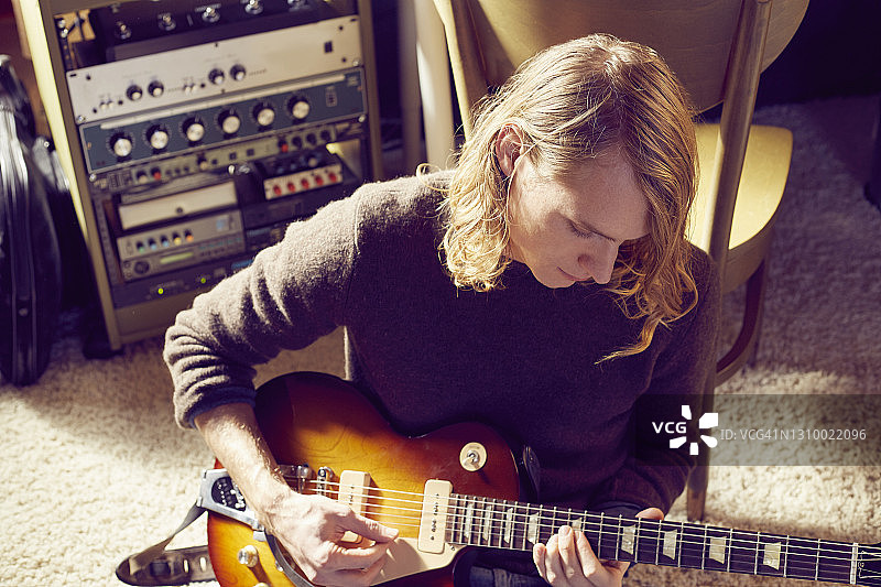在家中工作室弹吉他的年轻男子俯视角度照片图片素材