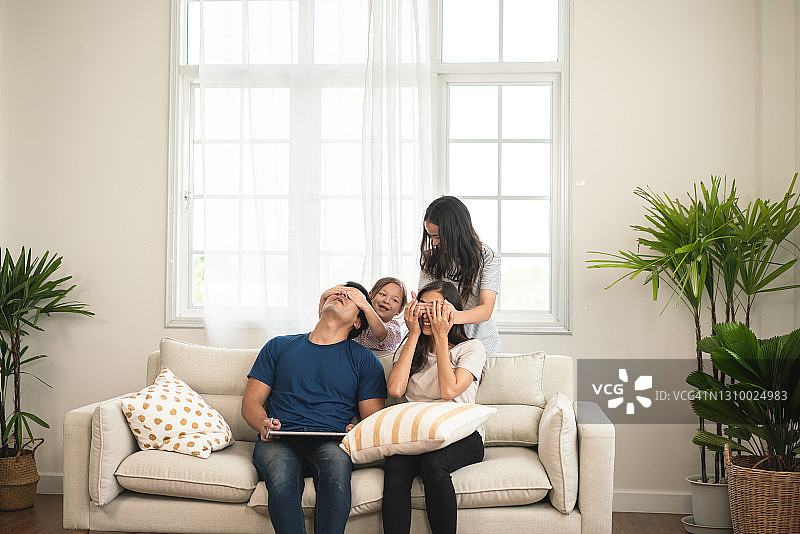 孩子们在玩耍，父母在沙发上休息并使用笔记本电脑图片素材