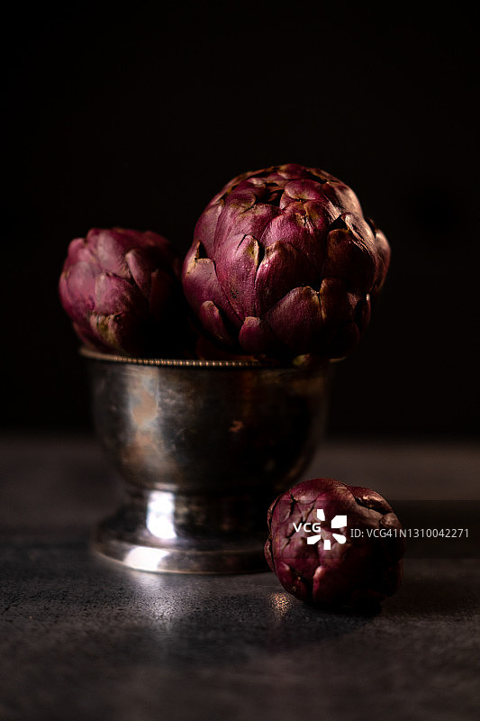 黑色桌子上碗里新鲜成熟的朝鲜蓟图片素材