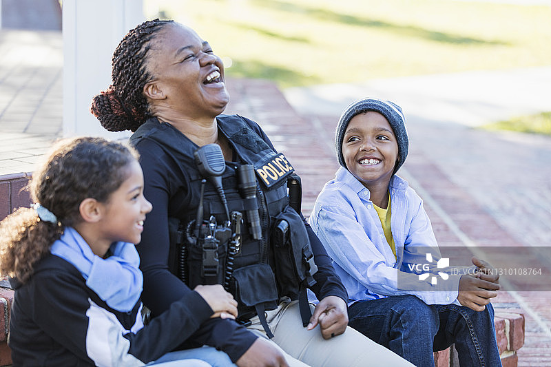 女警察在社区与两个孩子坐在一起图片素材
