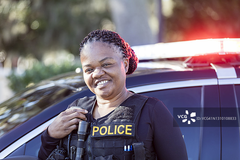 在巡逻车旁微笑的非裔美国女警察图片素材