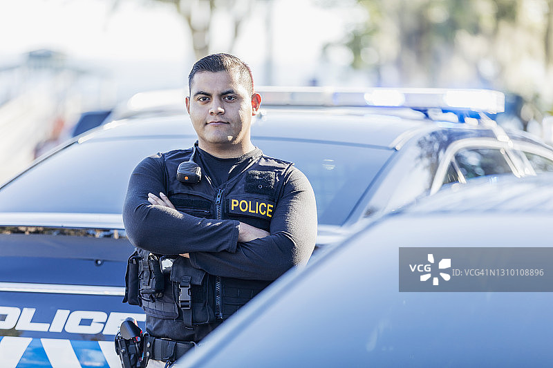 西班牙裔警官站在巡逻车旁图片素材
