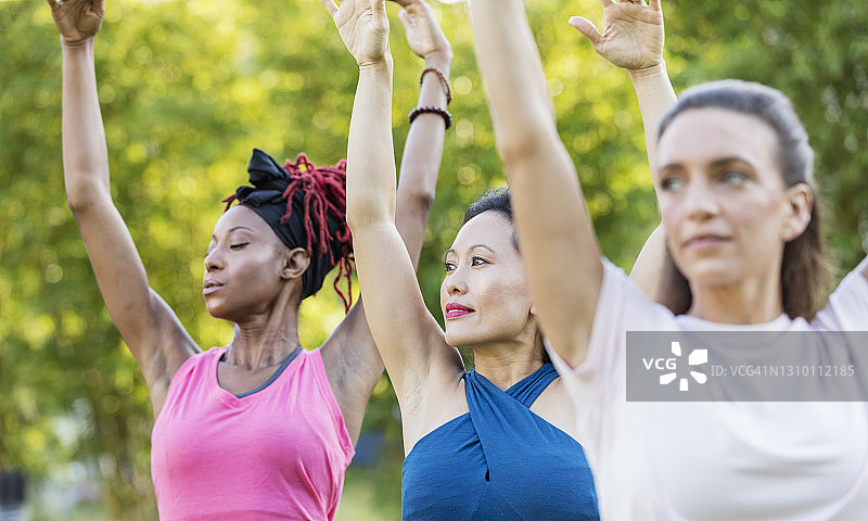 三名不同种族女性在户外上瑜伽课图片素材
