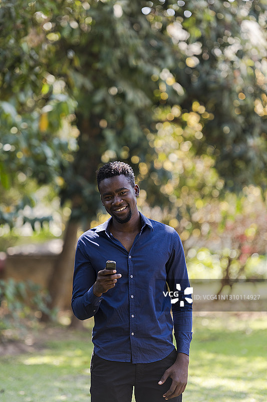 年轻的非洲男人拿着手机对着镜头微笑图片素材