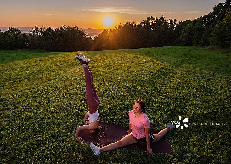 两个朋友在日出时于户外劈叉图片素材