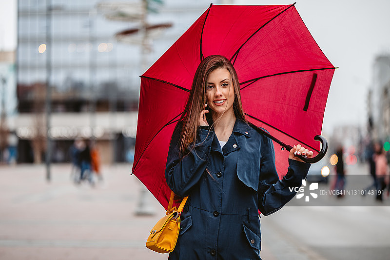 微笑女人在伞下打电话图片素材