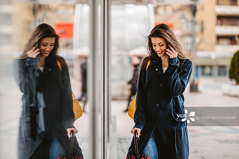 在商店橱窗里打电话和倒影的美丽女人图片素材