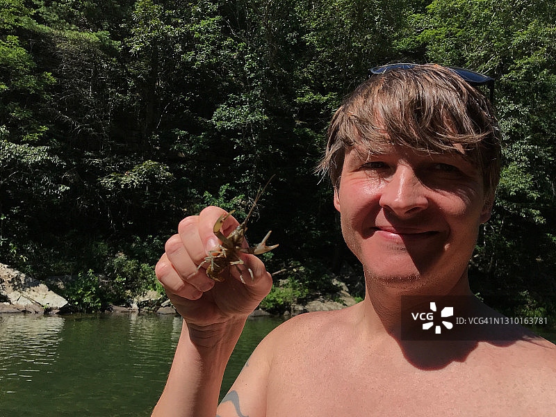 男人拿着在溪流中捕获的螯虾图片素材