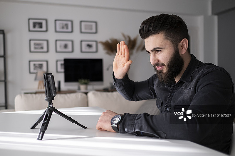 年轻男人在家中办公室通过视频通话挥手图片素材