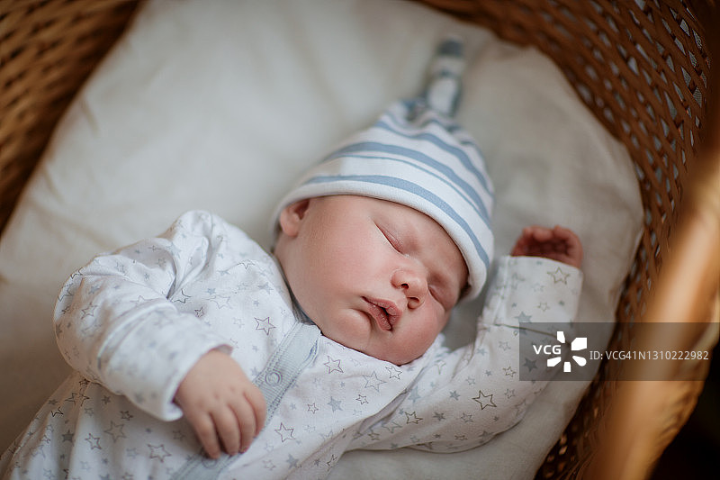 穿着白色针织面料和帽子，在床上甜蜜入睡的漂亮男孩-库存照片图片素材