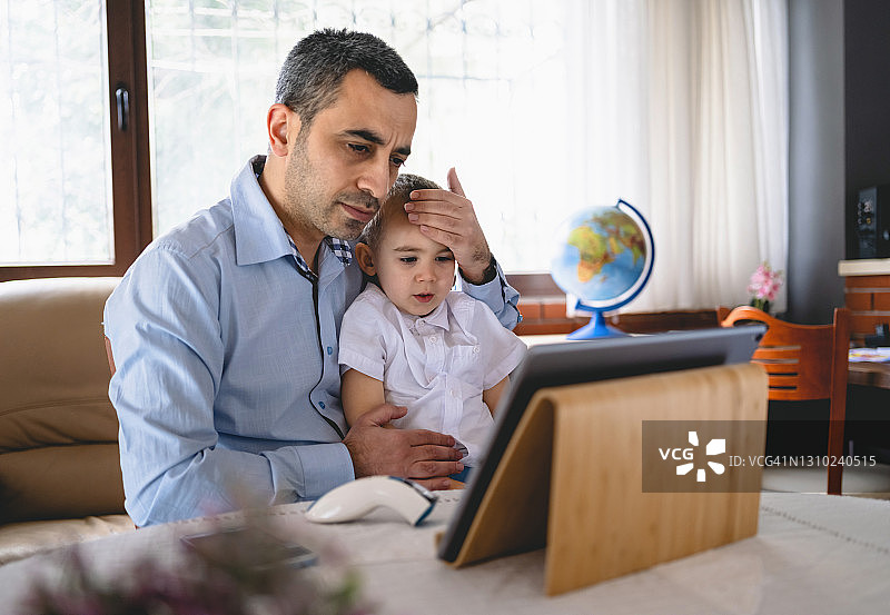 父亲通过视频通话向家庭医生咨询儿子的症状图片素材