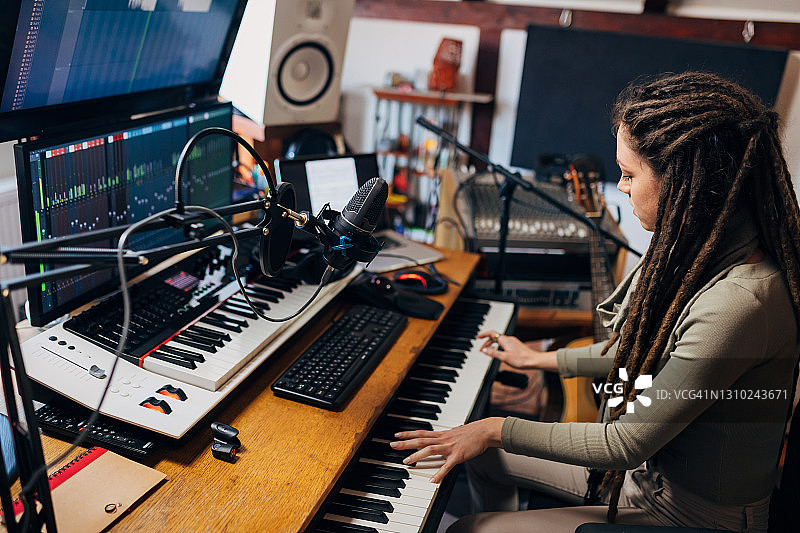 在新潮录音棚里使用电子音乐键盘进行音频制作的女艺术家图片素材