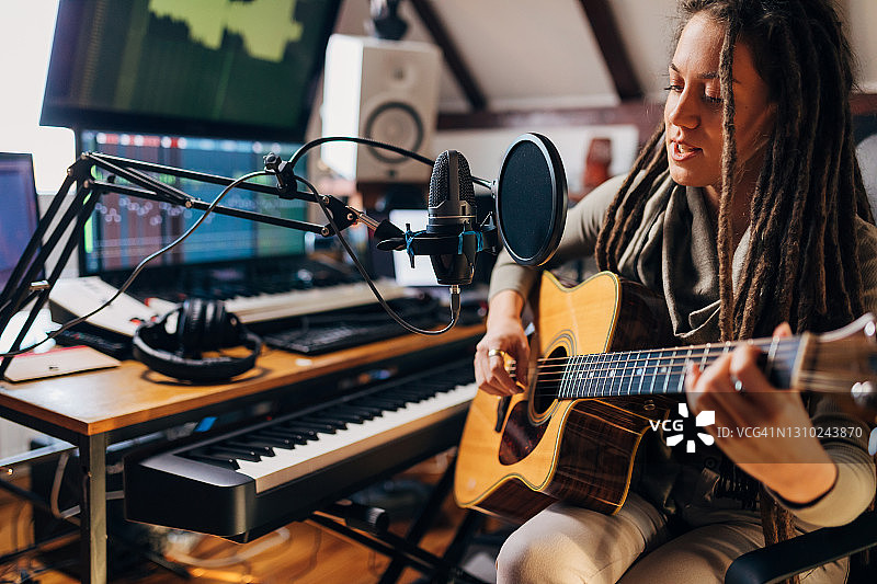 新锐艺术家在设备齐全的舒适录音棚里弹吉他唱歌图片素材