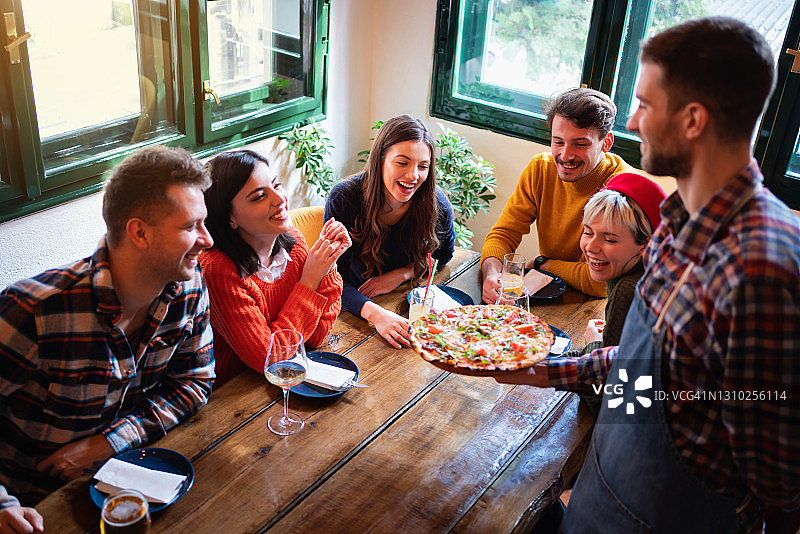 服务员在餐厅为餐桌送披萨图片素材