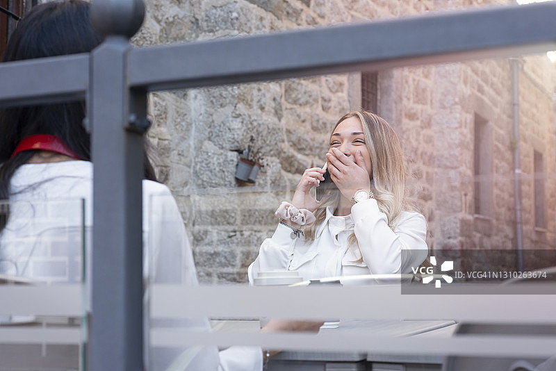 在路边咖啡馆使用智能手机的漂亮女人图片素材