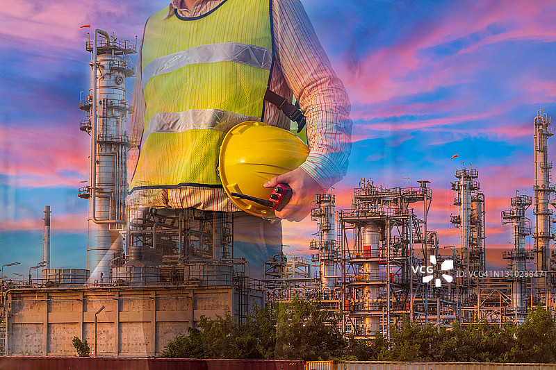 戴着安全帽的技师工程师与炼油厂背景的双重曝光图片素材