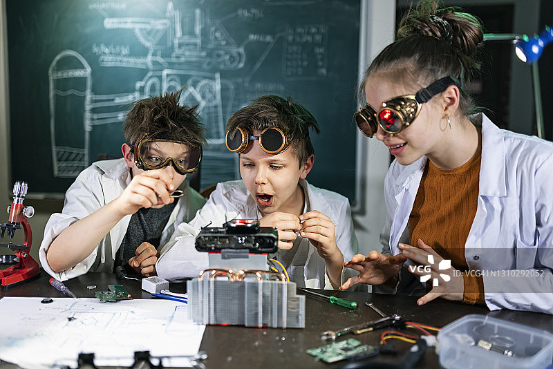 三位年轻的发明家正在建造一个神秘的装置图片素材